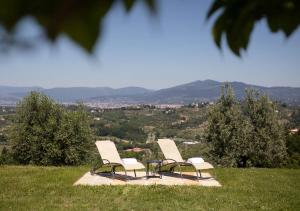 duas cadeiras e uma mesa no topo de uma colina em Tenuta Torre Rossa Farm & Apartments em Impruneta