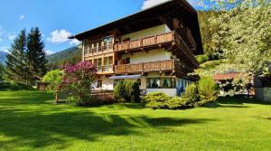 a large wooden house with a green yard at Pension Appartements Via Claudia in Lermoos