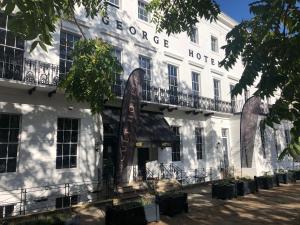 um hotel branco com uma placa na frente em The George em Cheltenham