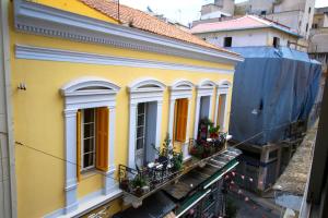 une maison jaune avec des fenêtres et des plantes sur un balcon dans l'établissement The monumental house, à Athènes