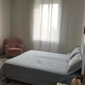 um quarto com uma cama, uma cadeira e uma janela em Casa Tigullio em Rapallo