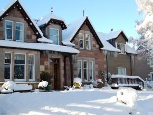 a house with snow on the ground in front of it at Glenan Lodge Self Catering in Tomatin