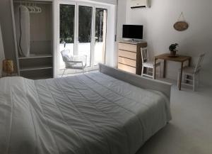 a white bedroom with a bed and a television at Magenta in Monopoli
