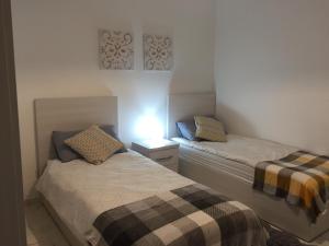 ein Schlafzimmer mit 2 Betten und einer Lampe an der Wand in der Unterkunft Bugibba Sunrise View Modern Apartment in St Paul's Bay
