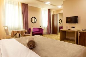 Habitación de hotel con cama, escritorio y TV. en West Shine Hotel, en Baku