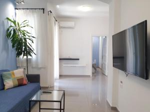ein Wohnzimmer mit einem blauen Sofa und einem TV in der Unterkunft KYMA Apartments - Athens Acropolis 5 in Athen