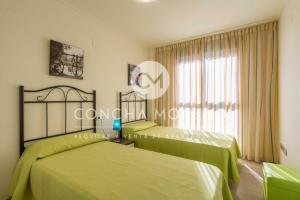 2 camas en una habitación con sábanas verdes en Vila Dorpesa X-CM, en Oropesa del Mar