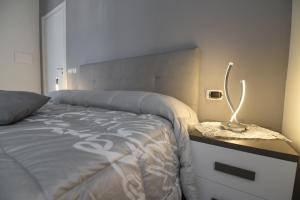 1 dormitorio con cama y mesita de noche con lámpara en L'Isola Del Postino Rooms en Procida