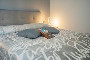 Una cama con dos almohadas y un libro. en L'Isola Del Postino Rooms, en Procida