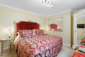 a bedroom with a large bed with a red bedspread at The Somerville in Torquay