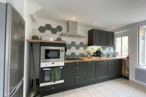 a kitchen with gray cabinets and a microwave at La mystérieuse maison du Robimouth in Saint-Satur
