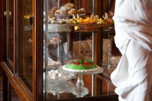 a display case with a green cake and other pastries at Q92 Noto Hotel in Noto