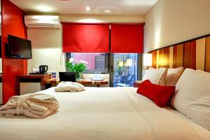 a bedroom with a large white bed with red accents at Lato Annex Boutique Rooms in Heraklio Town