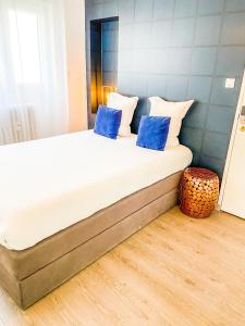 łóżko z niebieskimi poduszkami w pokoju w obiekcie Goodtime Apartments Strasbourg w Strasburgu