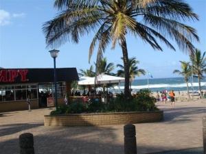 a beach with palm trees and a building and the ocean at Margate, Granada 102 in Margate