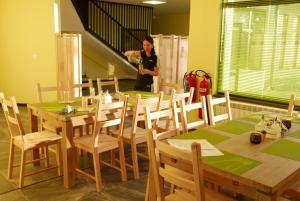 a woman standing in a room with tables and chairs at Къща за гости „Ботаника“ in Nadarevo
