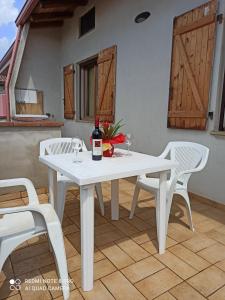 een witte tafel met 2 stoelen en een fles wijn bij Casa Cao Appartamento "L'Ulivo" in Nurachi