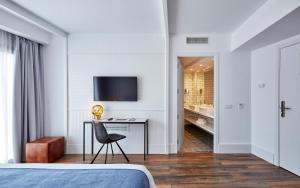 a bedroom with a bed and a desk and a television at Gran Hotel Flamingo-Adults Only older 18 years old in Lloret de Mar
