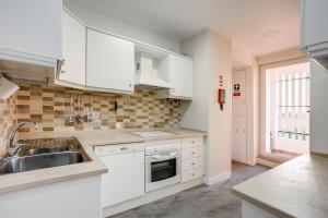 a kitchen with white cabinets and a sink at Amazing Tailor Made Penthouse by the Beach #1 in Oeiras
