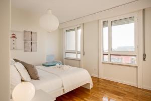 a white bedroom with a large bed and windows at Amazing Tailor Made Penthouse by the Beach #1 in Oeiras