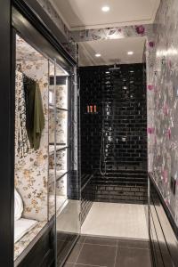 uma casa de banho com uma cabina de duche ao nível do chão ao lado de uma parede de tijolos em Q92 Noto Hotel em Noto