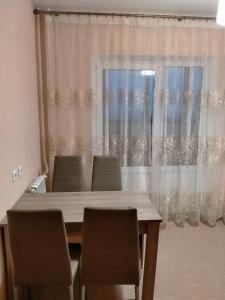 a dining room table with chairs in front of a window at Sunflower Aparts 36 in Voronezh