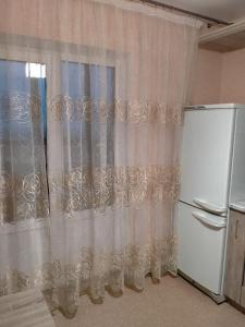 a kitchen with a white curtain and a refrigerator at Sunflower Aparts 36 in Voronezh