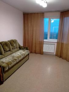 a living room with a couch and a large window at Sunflower Aparts 36 in Voronezh