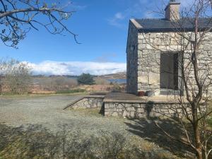 a stone building with a door in a field at Lough Meela Lodge in Dungloe