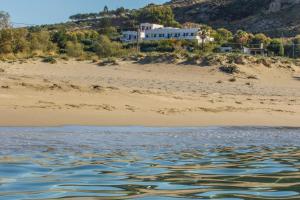 a house on a sandy beach next to the water at Plakias Bay Hotel in Plakias