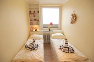 2 Betten in einem kleinen Zimmer mit Fenster in der Unterkunft Ferienwohnung Atlantik50 in Westerland