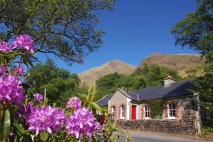 a house with a red door and mountains in the background at Delphi Lodge in Leenaun