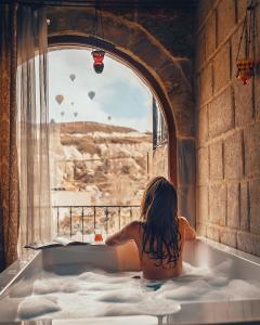 a little girl sitting in a bath tub looking out a window at Angel Cave Suite in Goreme