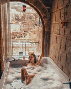 a woman is sitting in a bath tub at Angel Cave Suite in Goreme