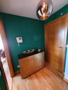 baño con pared verde y puerta de madera en Apartamento Rodeira, en A Illa de Arousa