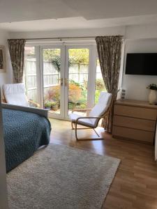 a bedroom with a bed and a chair and a television at Garden Studio in Marlow