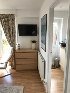 sala de estar con TV y vestidor con sofá en Garden Studio en Marlow