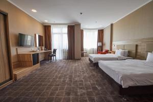 ロストフ・ナ・ドヌにあるRamada by Wyndham Rostov-on-Don Hotel and Spaのベッド2台とテレビが備わるホテルルームです。
