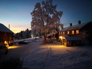 Una casa en la nieve por la noche con luces encendidas en Yttervik gard, en Steinkjer