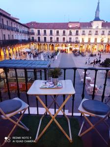 una mesa y sillas en un balcón con una calle de la ciudad en Viva León, en León