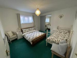 a bedroom with two beds and a chair and a mirror at Barracuda, Beachside Apartment in Benllech