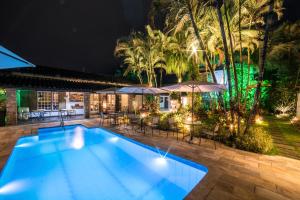 a swimming pool at night with tables and umbrellas at Casa Nostra Boutique Hotel in Paraty