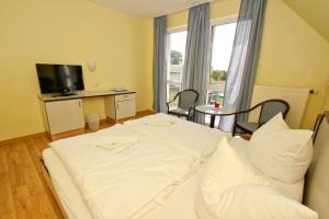 a room with a white bed and a television at F-1010 Strandhaus Mönchgut B&B Doppelzimmer Nr 35 in Lobbe