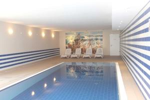 a swimming pool with chairs and a painting on the wall at strandnah, Ferienwohnung mit Sauna- und Schwimmbadnutzung - Strandresidenz Baabe FeWo1-30 in Baabe