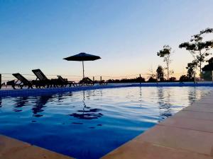 a swimming pool with chairs and an umbrella at Herdade dos Salgados do Fialho in Faro