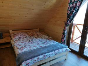 a bed in a wooden room with a window at Domek na wzgórzu "WILK" in Świątkowa Mała
