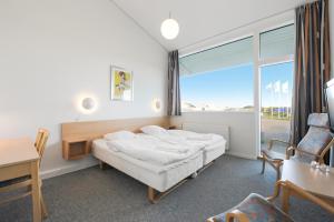 a bedroom with a bed and a desk and a window at Landal Hotel Fyrklit in Hirtshals +18 photos