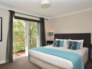 een slaapkamer met een groot bed en een glazen schuifdeur bij Villa 3br Fiano Villa located within Cypress Lakes Resort in Pokolbin