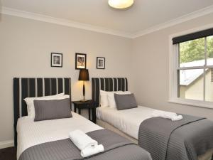 um quarto com 2 camas e uma janela em Villa 3br Margarita Villa located within Cypress Lakes Resort em Pokolbin