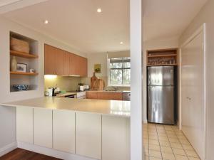 a kitchen with white cabinets and a stainless steel refrigerator at Villa 3br Tempranillo Villa located within Cypress Lakes Resort in Pokolbin